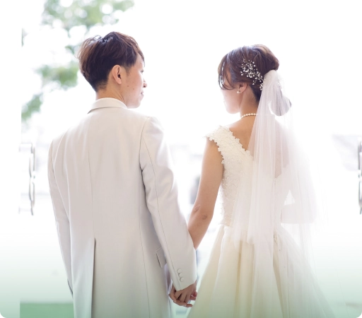結婚式で手を取り合う新郎新婦。幸せそうな笑顔で互いを見つめ合う。