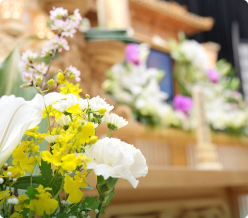 白い菊やユリが供えられた厳かな葬儀の祭壇。故人を偲ぶ静かな空間。