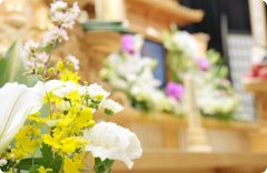 白い菊やユリが供えられた厳かな葬儀の祭壇。故人を偲ぶ静かな空間。